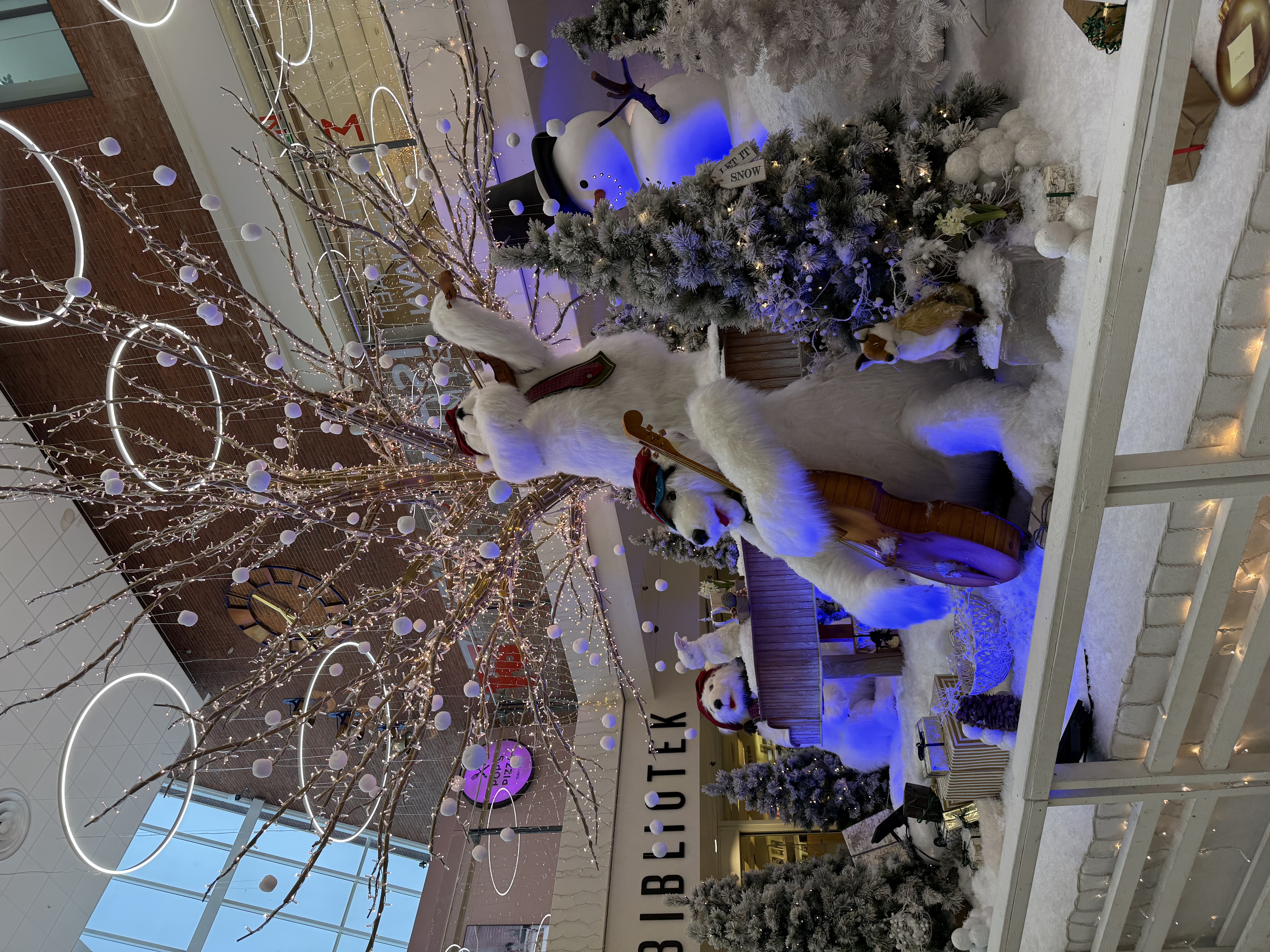 Kvindelig medarbejder med nissehue smiler foran julepyntet butik